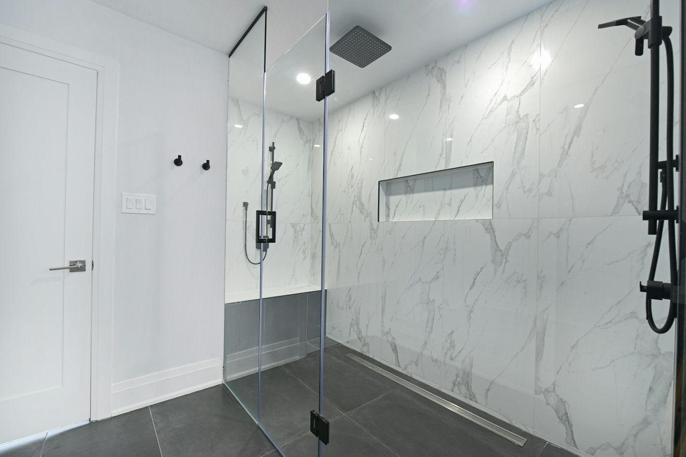 Luxurious modern bathroom with marble walls and a glass-enclosed walk-in shower