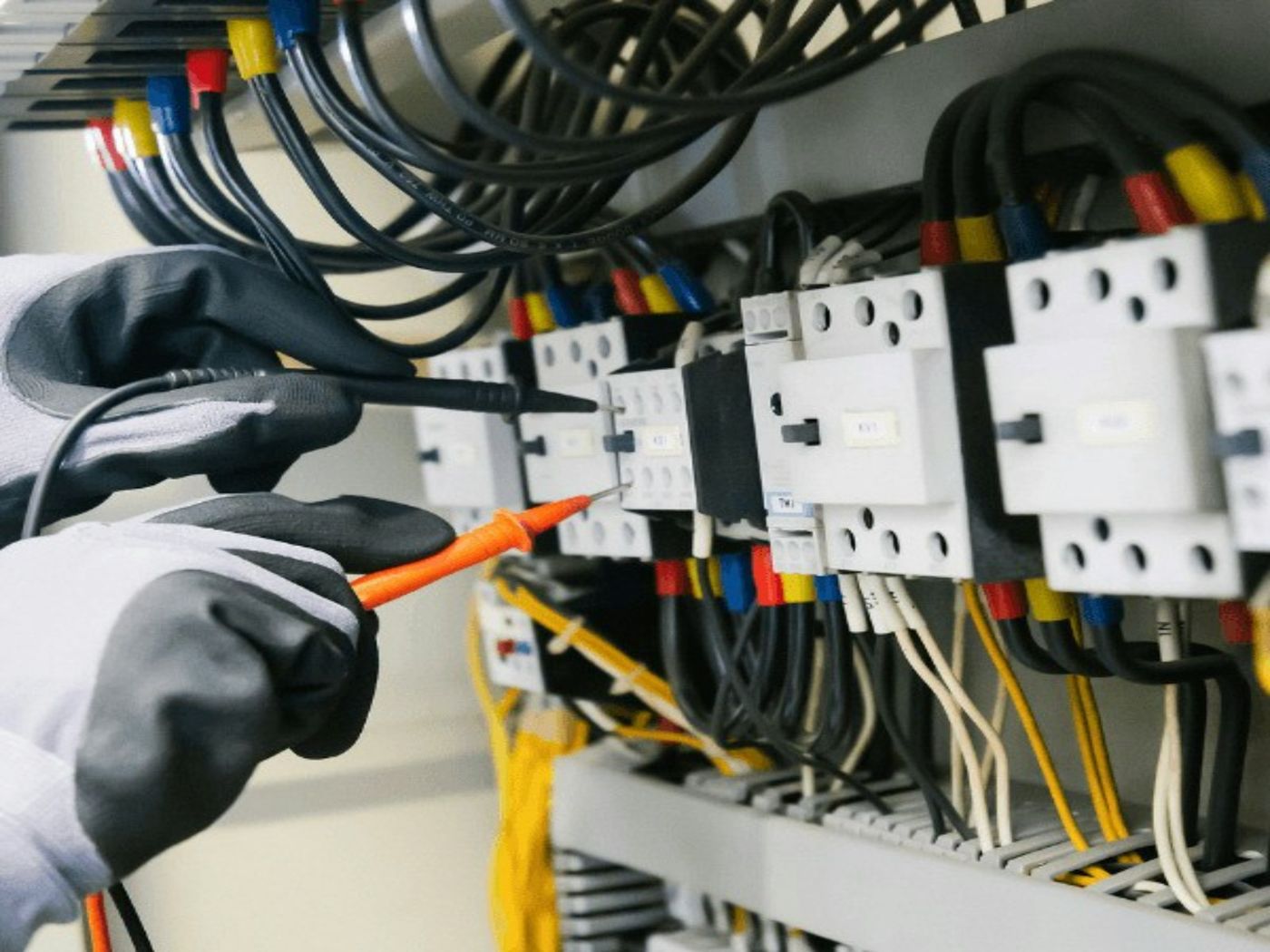Electrician testing a modern circuit panel with a multimeter during a rewiring project