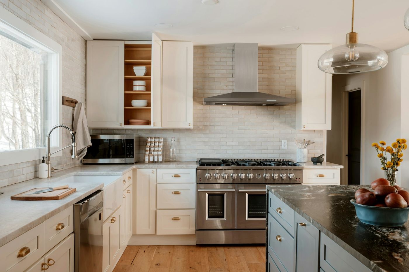 Modern renovated kitchen with white cabinetry, stainless steel appliances and a marble island